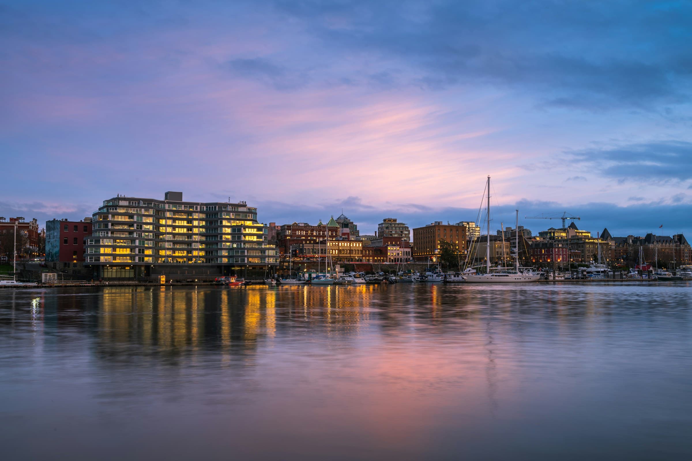 Victoria's Inner Harbour skyline reflected in the water beneath a pink-and-blue evening sky